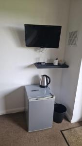 a small refrigerator in a room with a tv on the wall at Relaxing Room With Ensuite Rutland Point in Morcott