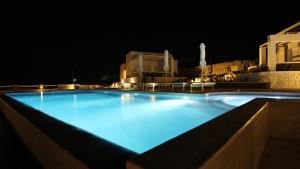 a large swimming pool lit up at night at Lemon Tree Houses in Áno Meriá