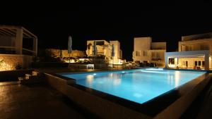 a large swimming pool at night with buildings at Lemon Tree Houses in Áno Meriá