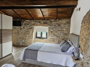 1 dormitorio con cama y pared de piedra en Quinta Vilar de Lobos, en Arcos de Valdevez