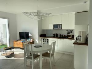 a kitchen with a white table and chairs and a kitchen with a table at Maison neuve zone coulée verte menant a l'océan in Saint-Gilles-Croix-de-Vie