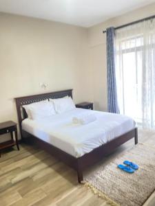 een slaapkamer met een groot wit bed met een raam bij Yohana Residences in Nairobi