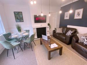 ein Wohnzimmer mit einem Tisch und ein Wohnzimmer mit einem Sofa in der Unterkunft Group stays Wolverhampton M6 J10 in Bilston