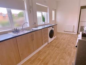 a kitchen with a sink and a washing machine at Long stay contractor accommodation Wolverhampton in Bilston +23 photos