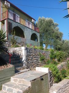 a building with a balcony on top of a stone wall at Sminos Farm House E4 path, Γυθειο 