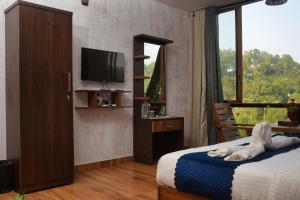 Schlafzimmer mit einem Bett, einem TV und einem Fenster in der Unterkunft TREE6 WAYANAD in Vythiri