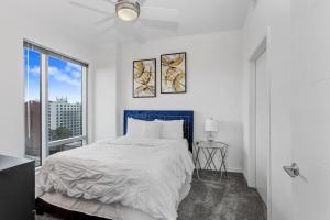 a white bedroom with a large bed and a window at Stunning 2-Bed Condo with Panoramic DT Tampa Views in Tampa