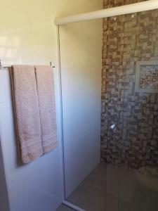 a shower with a glass door and a towel at Chalé mirante da colina in Visconde De Maua