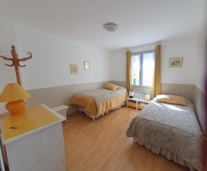 a bedroom with two beds and a table and a window at Le Temps d'une Pause in Andert-et-Condon