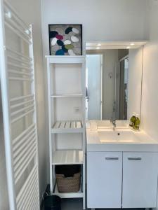 uma casa de banho branca com um lavatório e um espelho em Magnifique appartement avec sa grande terrasse em Touques