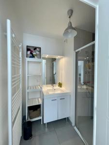 uma casa de banho branca com um lavatório e um espelho em Magnifique appartement avec sa grande terrasse em Touques