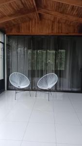 two white chairs sitting in a room with windows at Monteverde Guesthouse in Monteverde Costa Rica