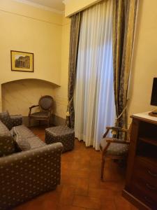 モンテ・サン・サヴィーノにあるHotel Logge Dei Mercantiのリビングルーム(ソファ、椅子、カーテン付)