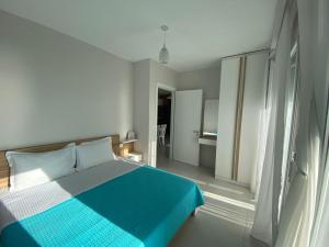 1 Schlafzimmer mit einem blauen und weißen Bett und einem Badezimmer in der Unterkunft Avenir Apartment in Durrës