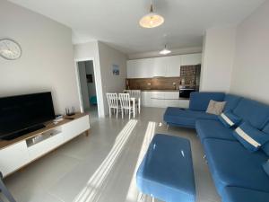 ein Wohnzimmer mit einem blauen Sofa und einem TV in der Unterkunft Avenir Apartment in Durrës