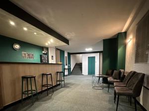 - un hall avec un bar avec des tabourets et des murs verts dans l'établissement Hôtel Le Valéran, à Ligny-en-Barrois