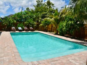 a swimming pool in a yard with chairs and trees at Tropical Retreat Near Beaches, Cruise Terminals in Merritt Island