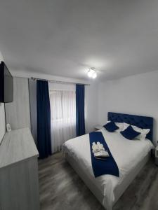 1 dormitorio con 1 cama con almohadas azules y blancas en CASA RAUL, en Poiana Mărului