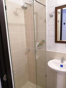 een douche met een glazen deur naast een wastafel bij Orquidia 12 in Salento