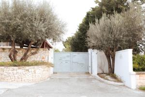 a driveway with a blue gate and two trees at Luoghi di Puglia in Ostuni