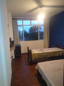 a bedroom with two beds and a large window at Apartamento Pé na Areia com Vista Mar e Wi-fi LOFTJL com 01 vaga de garagem sujeita a disponibilidade in Santos