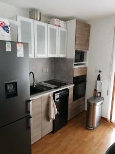 a kitchen with white cabinets and a black refrigerator at Appartement "ENTOURLOUP" classé 2 étoiles in Le Dévoluy