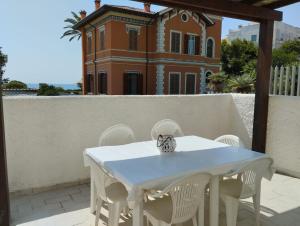 une table et des chaises blanches avec une maison en arrière-plan dans l'établissement Santa Marinella Appartamento centralissimo a 2 passi dal mare, à Santa Marinella