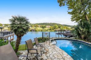 uma piscina com cadeiras e uma palmeira junto a um rio em Lake Austin Lakeside Retreat em Austin