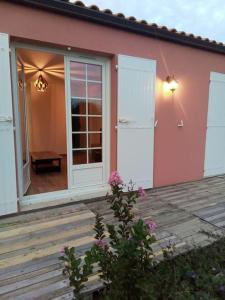 a pink house with a door and a wooden deck at Maison 2 pièces, 4 personnes in Le Loroux-Bottereau