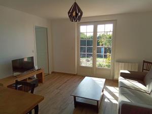 a living room with a couch and a tv at Les Noisetiers in Le Loroux-Bottereau