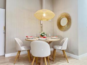 uma mesa de jantar com cadeiras brancas e um espelho em COQUETO APARTAMENTO em Torrelavega