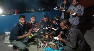 Green Leaf Guest House ColIege Road Sreemongal في سريمانغال: مجموعة من الرجال يأكلون الطعام حول الشواية