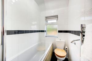 a white bathroom with a toilet and a tub at London serviced apartments BAFOG in Barking