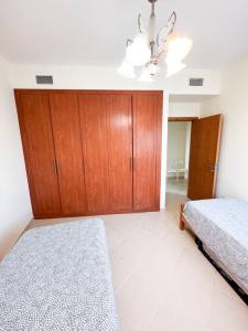 1 Schlafzimmer mit 2 Betten und einem Holzschrank in der Unterkunft Spacious 2 Bed Apt at Marina in Dubai