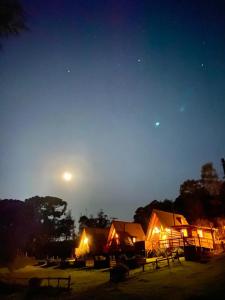 um grupo de alojamentos de noite com a lua no céu em Sítio CRIA - Hospedagem Sustentável & Experiências Rurais em Três Coroas