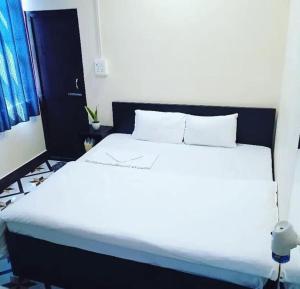 una camera con letto bianco e testiera nera di OYO Flagship The Thangal Hotel a Imphal