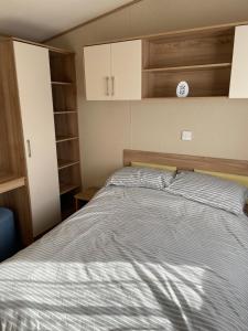 een slaapkamer met een bed en een klok aan de muur bij 8 Berth family caravan Selsey West Sussex in Selsey