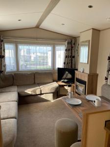uma sala de estar com um sofá e uma mesa em 8 Berth family caravan Selsey West Sussex em Selsey