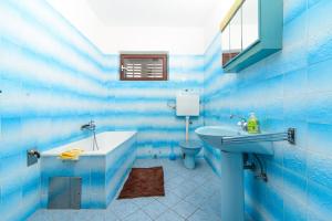 a blue bathroom with a sink and a tub and a toilet at Apartmani Katica in Kornić