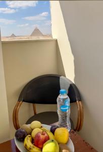 une assiette de fruits et une bouteille d'eau sur une chaise dans l'établissement pyramids guest house, au Caire