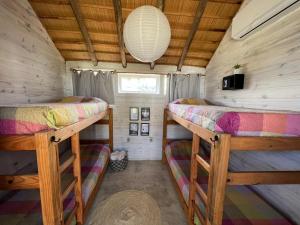 a bedroom with two bunk beds in a tiny house at Pueblo Arriba Hostel in Punta Del Diablo