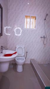 a white bathroom with a toilet and a sink at Cogent Apartments in Uyo