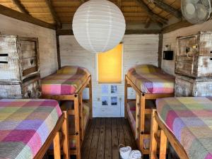 a room with three beds in a wooden cabin at Pueblo Arriba Hostel in Punta Del Diablo