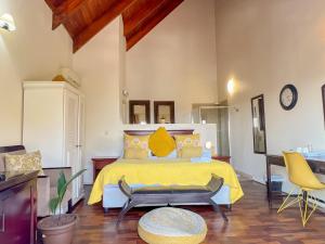 a bedroom with a yellow bed and two chairs at Amoris Guesthouse In Waterkloof Ridge in Pretoria