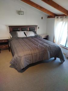 Un dormitorio con una cama grande y una ventana. en Cabañas Vera, en Punta Arenas