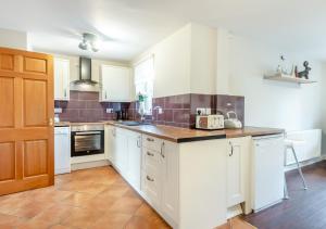a kitchen with white cabinets and brown tile floors at Pebble Cottage in Little Walsingham