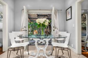 una sala da pranzo con tavolo in vetro e fiori bianchi di Highland Haven Estate a Los Angeles