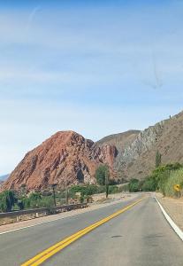 un camino vacío con una montaña en el fondo en El Shaddai en Tilcara