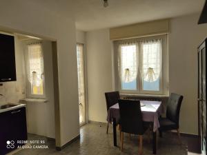 a dining room with a table and chairs and windows at Appartamento centro Brusson. in Brusson