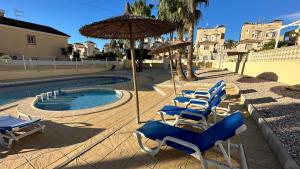 eine Gruppe Stühle und ein Sonnenschirm neben einem Pool in der Unterkunft Casa Blue Lagoon KLIMA FREE WIFI POOL SAT TV in San Miguel de Salinas